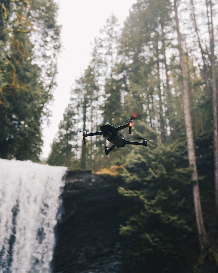 A drone captures a scenic view over a waterfall surrounded by forest in BC.
